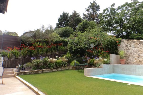 Aménagement d'un jardin fleuri sur Saint-Jean-de-Luz avec entrée, massifs fleuris et piscine.