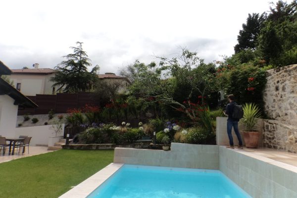 Aménagement d'un jardin fleuri sur Saint-Jean-de-Luz avec entrée, massifs fleuris et piscine.