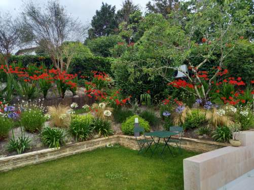 Aménagement d'un jardin fleuri sur Saint-Jean-de-Luz avec entrée, massifs fleuris et piscine.